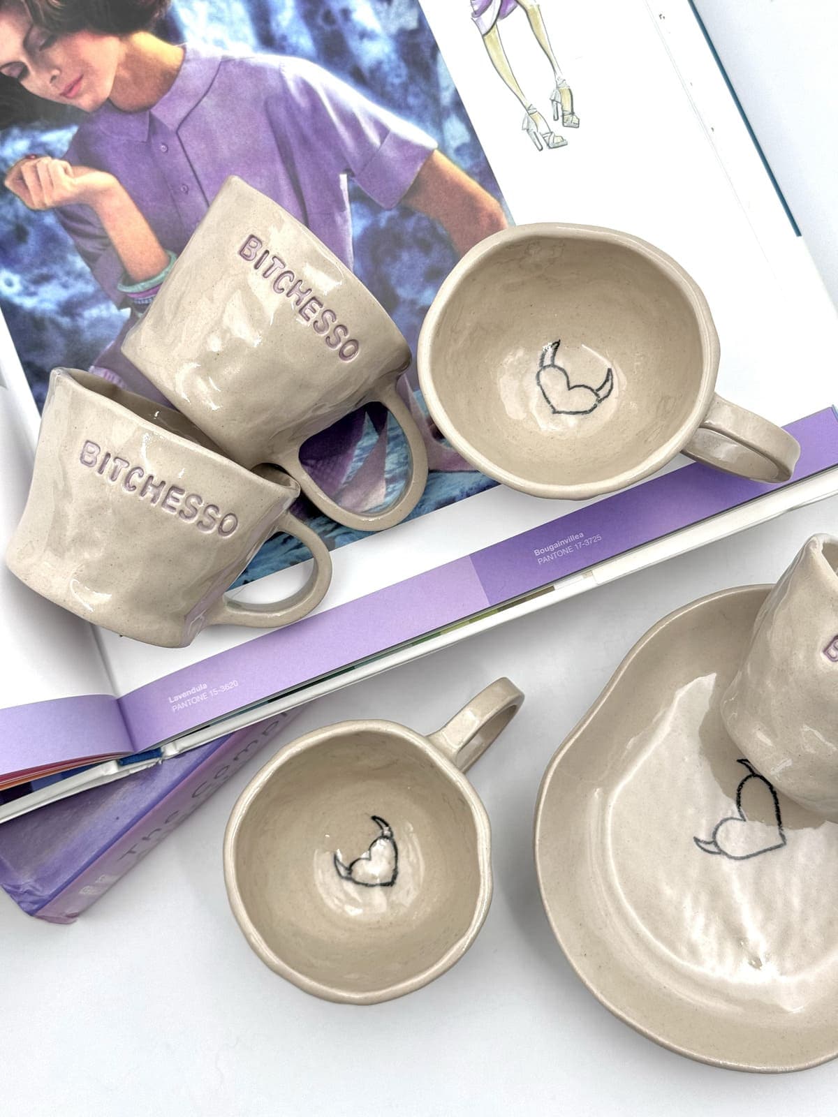 Ręcznie robiona błyszcząca beżowa ceramiczna filiżanka espresso, nieregularna, z liliowym BITCHESSO i sercem z rogami wewnątrz.